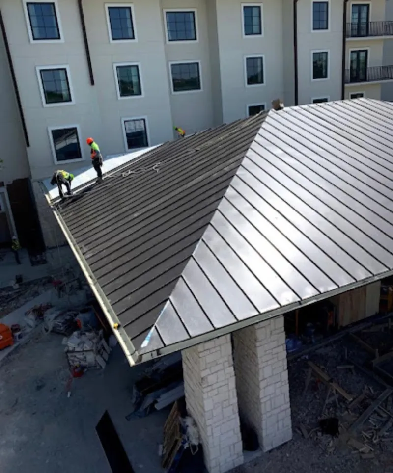 Crew installing standing seam metal roof panels on a commercial project in Clemmons